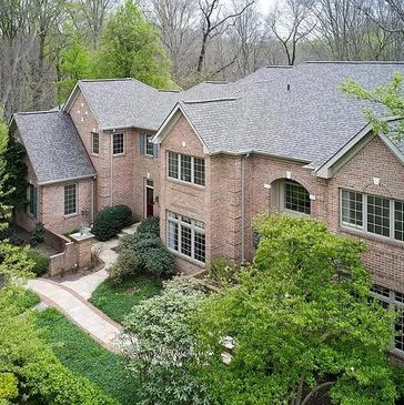 Aerial view of a large brick home surrounded by trees and landscaping.